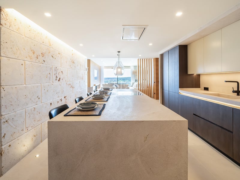 Cuisine contemporaine avec un grand îlot en pierre, des armoires en bois sombre et un mur en pierre naturelle.