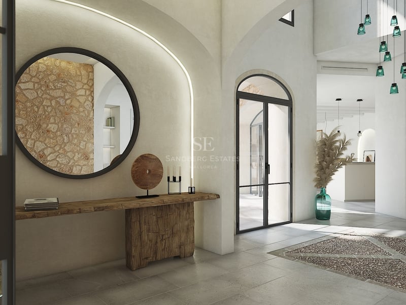 Entrée de villa spacieuse avec arches, mur en pierre naturelle, miroir rond et console en bois sculpté.
