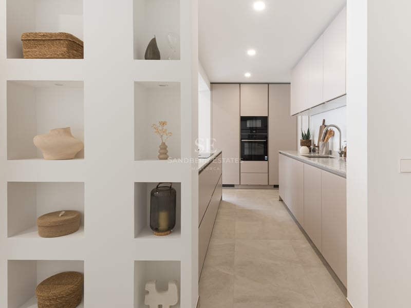 Cuisine moderne avec des meubles taupe et un mur comprenant des niches décoratives avec des objets d'art.