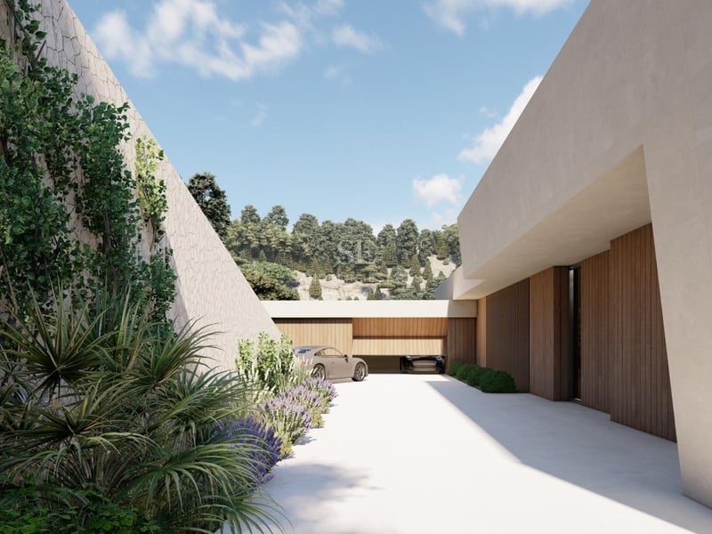 Allée de villa de luxe avec murs en pierre naturelle, portes de garage en bois et bougainvilliers.