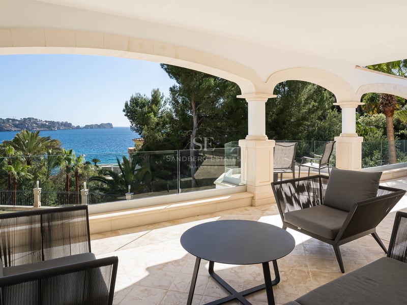 Überdachte Steinterrasse mit Rundbögen, Glasgeländern und modernen Möbeln mit Blick auf das Mittelmeer.