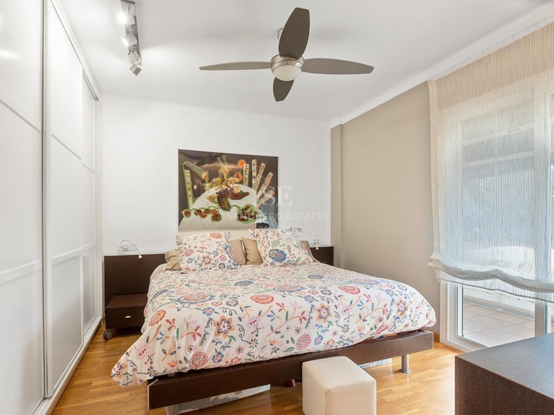 Schlafzimmer mit Eichenparkett, weißen Einbauschränken, Doppelbett und Glastür zur Terrasse.