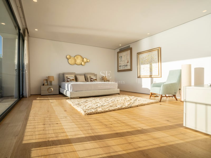 Helles, modernes Hauptschlafzimmer mit Eichenparkett, bodentiefen Glastüren und zeitgenössischen Möbeln.