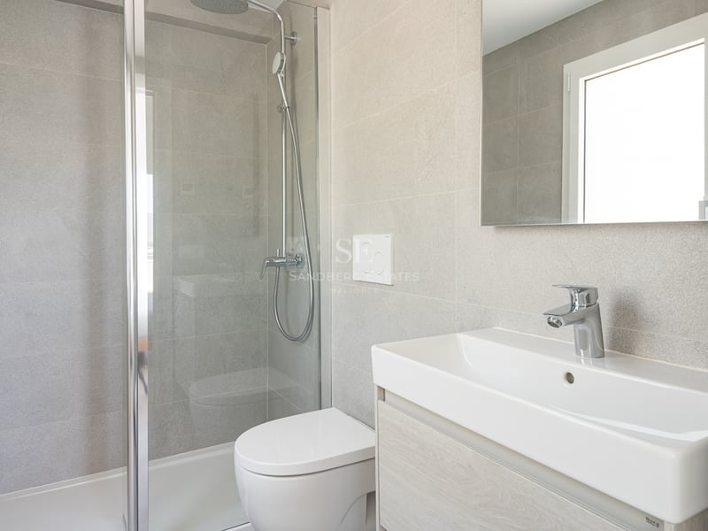 Salle de bain contemporaine avec carrelage effet pierre grise, douche vitrée, WC suspendu et meuble vasque blanc.