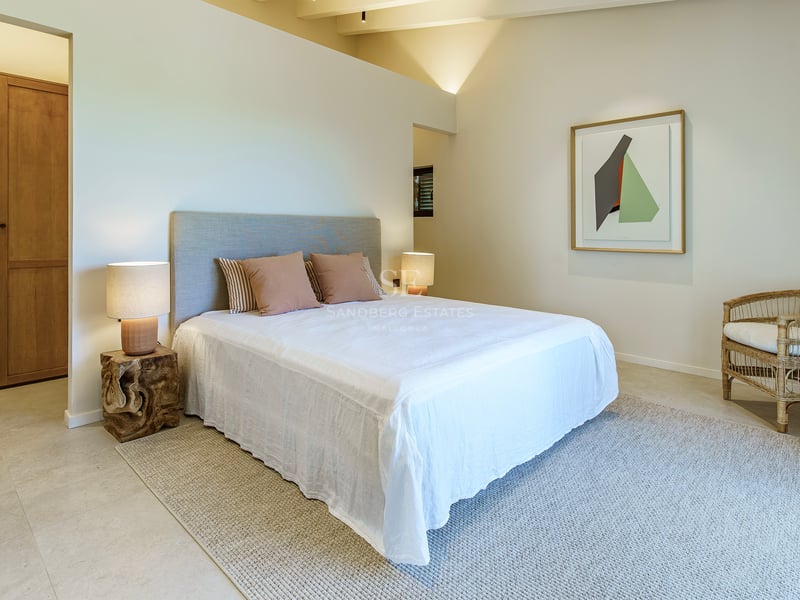 Helles Hauptschlafzimmer mit Gewölbedecke, Nachttischen aus Naturholz und Textilien in neutralen Tönen.