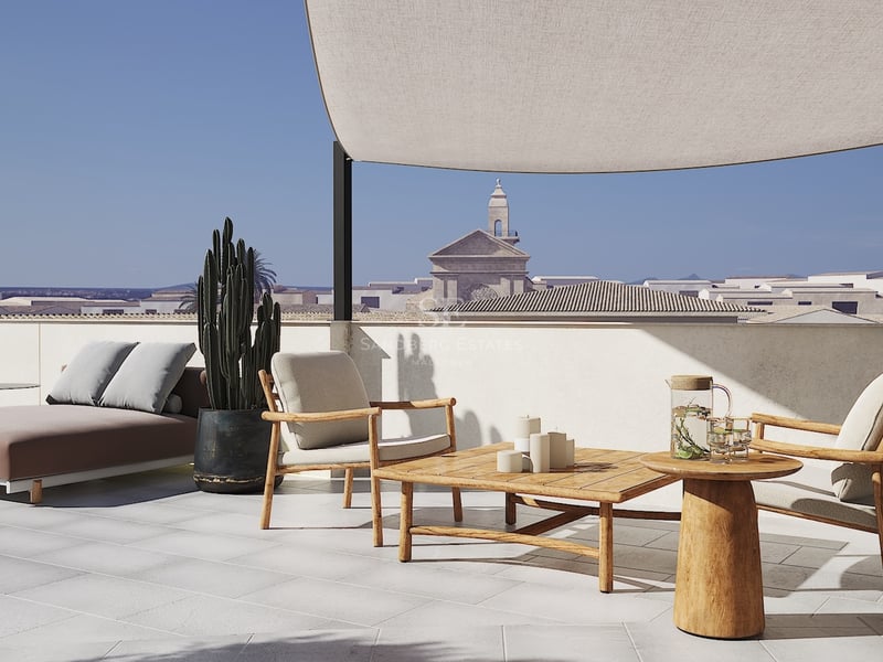 Terrasse moderne avec fauteuils en teck, voile d'ombrage et vue sur un clocher d'église historique.