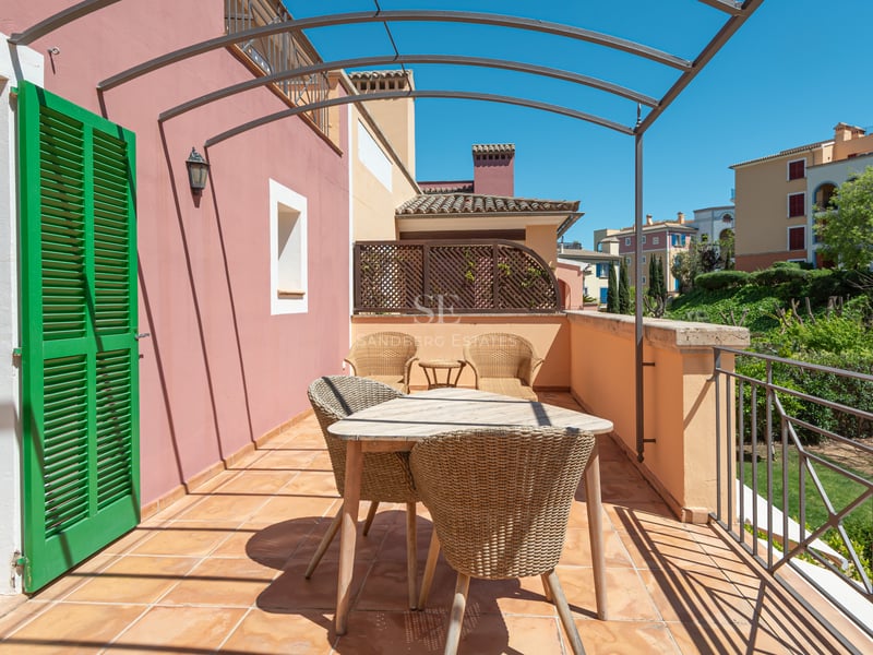 Private terrace with terracotta tiles, wicker furniture, and a metal pergola overlooking lush greenery.