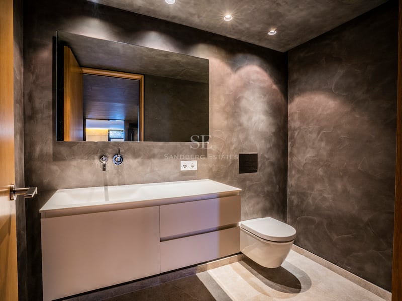 Modernes Badezimmer mit anthrazitfarbenen Mikrozementwänden, weißem Hängewaschtisch und großem Spiegel.