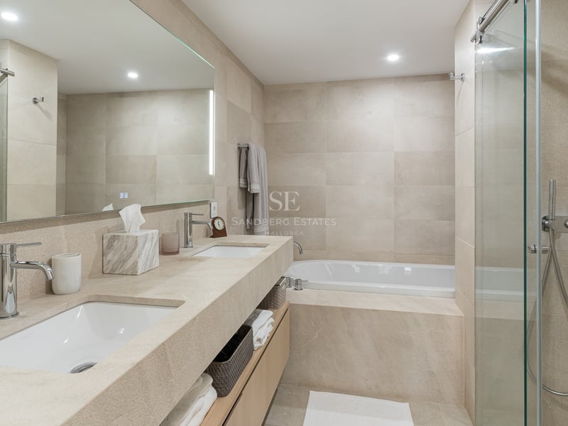 Modern bathroom featuring a double vanity with integrated stone sinks, a bathtub, and a glass-enclosed shower.