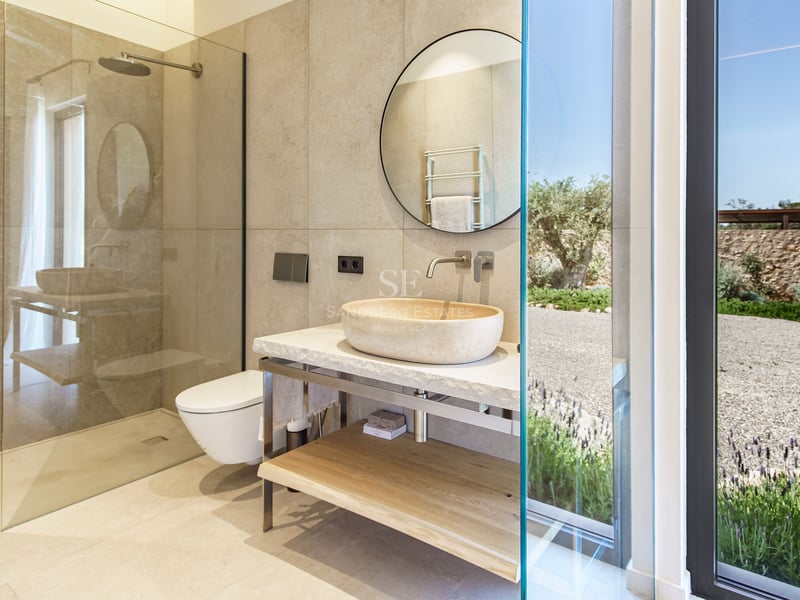 Zeitgenössisches Badezimmer mit Naturstein-Aufsatzwaschbecken, Rundspiegel und ebenerdiger Dusche.