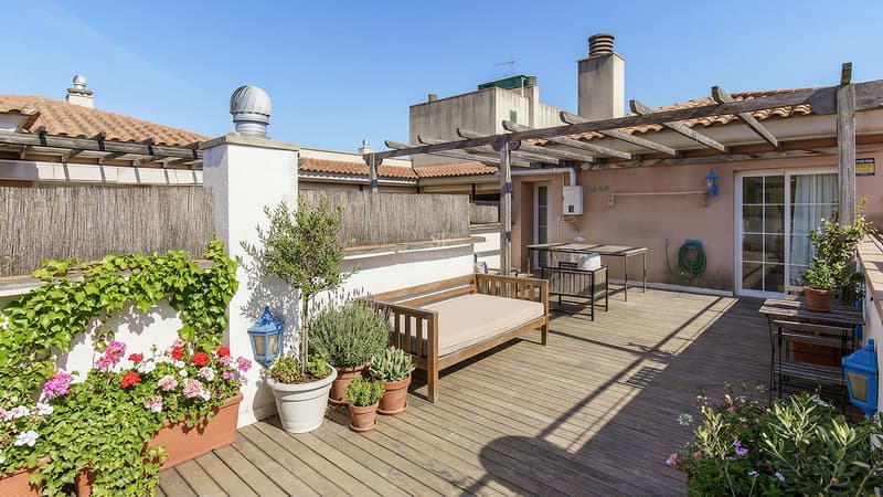 Sonnige Dachterrasse mit Holzdeck, Pergola, blühenden Pflanzgefäßen und Loungemöbeln.