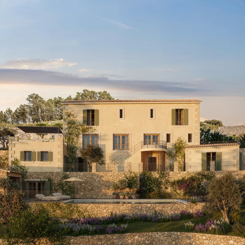 Façade en pierre d'une villa de trois niveaux avec volets verts, piscine et jardins en terrasses au coucher du soleil.