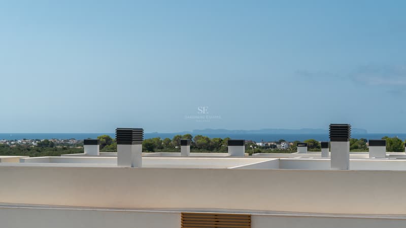 Vue depuis un toit-terrasse moderne vers la mer Méditerranée et une île lointaine à travers la pinède.