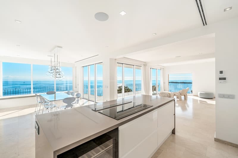 Helle, moderne Küche und Esszimmer mit großen Fenstern, die einen weiten blauen Ozean zeigen.