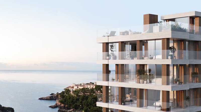 Immeuble moderne à plusieurs étages avec façade en pierre, balcons en verre et vues panoramiques sur la mer.