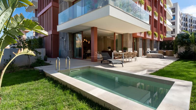 Luxury terrace with private plunge pool, outdoor dining set, sun lounger, and green lawn by a modern apartment building.