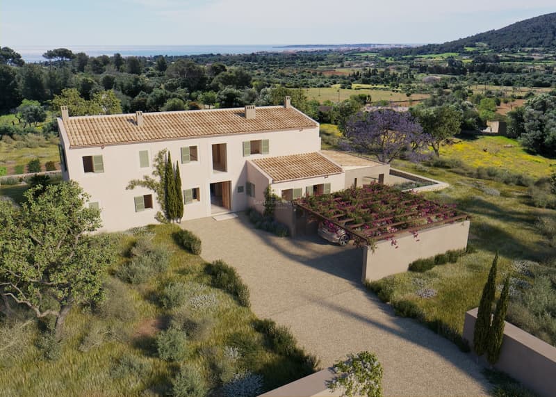 Vue en hauteur d'une villa beige de deux étages avec toit en terre cuite, volets verts et allée de gravier face à la mer.