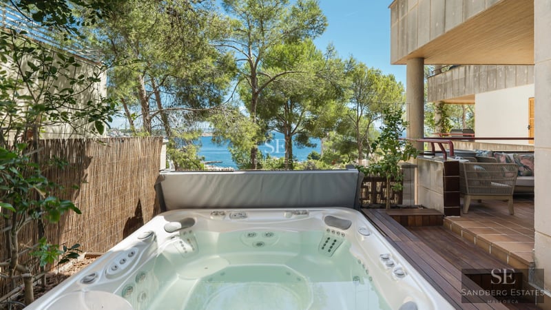 Spacious living room with window walls, fireplace, light wood floors, and minimalist decor. Panoramic views of nature.