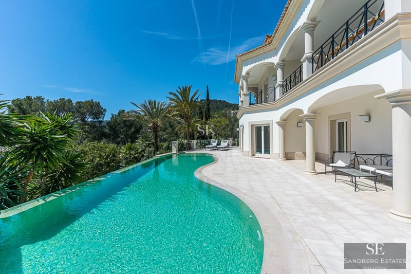 Spacious living room with floor-to-ceiling windows, designer sofas, modern fireplace and panoramic views. Natural and warm lighting.