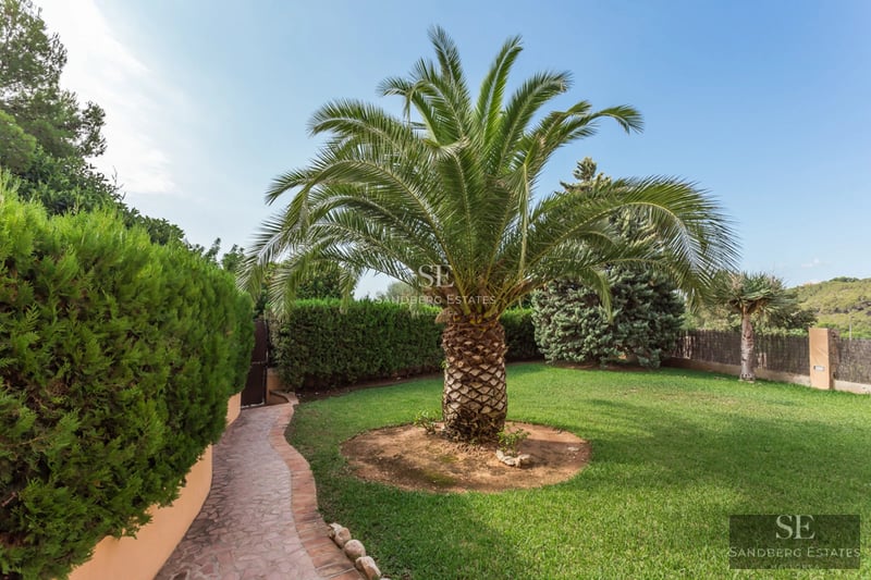 Modern villa view with large terrace, infinity pool, sun loungers, and minimalist outdoor furniture. Well-maintained garden.