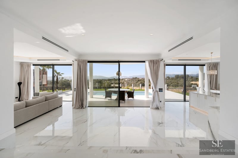 Exterior view of a modern villa featuring an infinity pool, spacious terraces, lush garden, and minimalist architectural design.