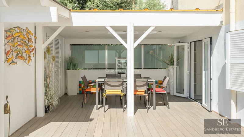 Amplia piscina bordeada de tumbonas, con una moderna casa de diseño minimalista al fondo y exuberante vegetación.