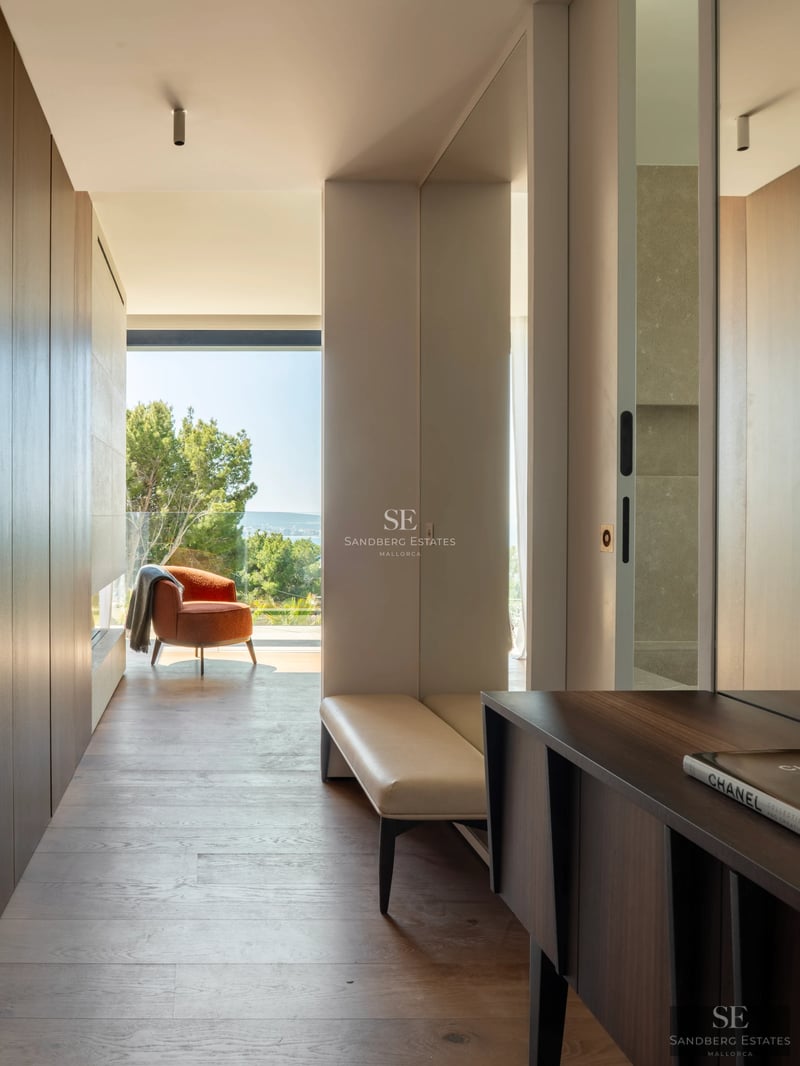 Amplio salón con ventanales al mar, suelos de madera clara, y diseño minimalista. Vistas panorámicas y mucha luz natural.