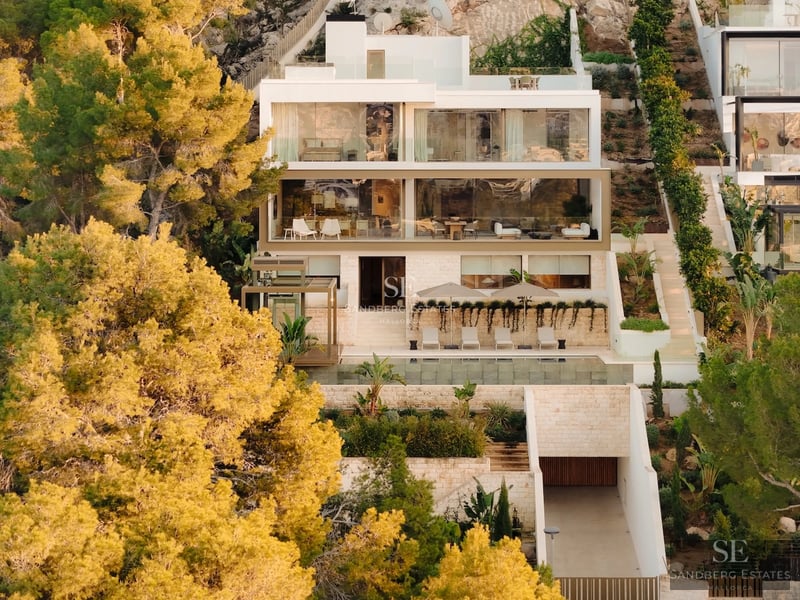 View of a modern villa featuring an infinity pool, manicured gardens, and minimalist architecture. Warm lighting and elegant outdoor furniture.