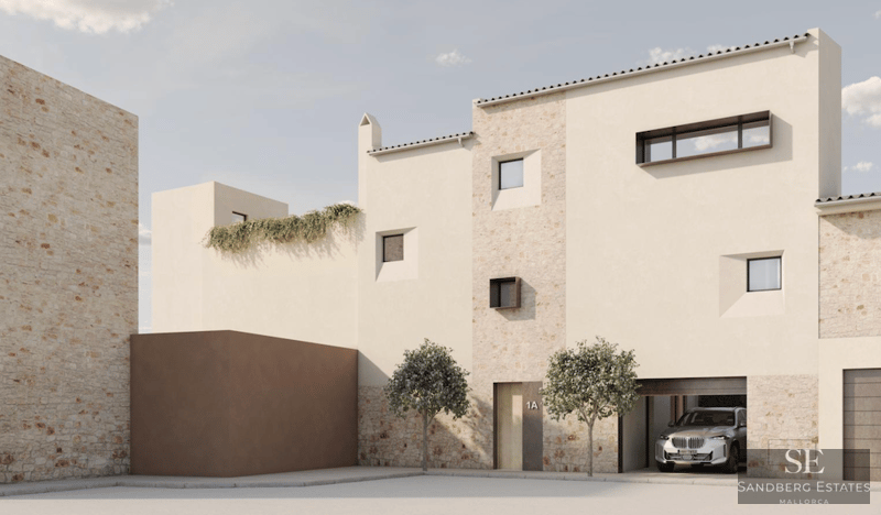 Edificio moderno de piedra y estuco con ventanas minimalistas y un coche en el garaje bajo la luz del día.