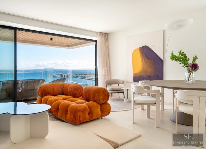 Spacious living room featuring large windows, ocean views, modern furniture, a fireplace and terrace access. Minimalist and elegant design.