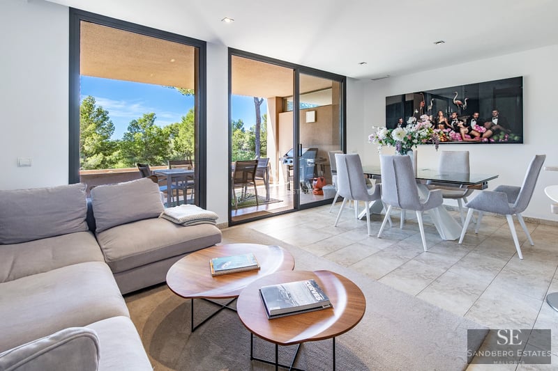 Vista de una villa moderna con piscina desbordante, tumbonas y exuberante vegetación. Arquitectura minimalista y diseño paisajístico.