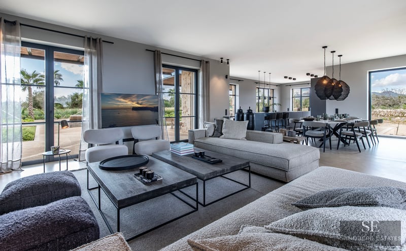 Spacious modern living room with grey sofas, wooden coffee tables, and dining area looking out to a garden.