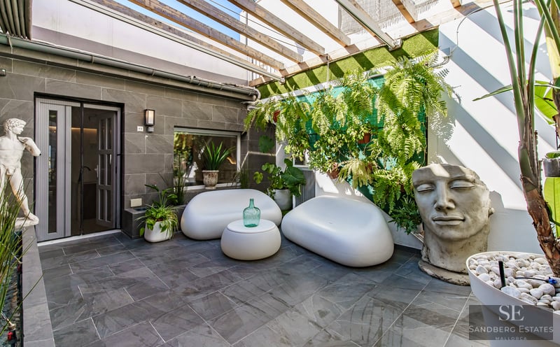 Modern Terrace with Designer Furniture and Sculptures Contemporary patio with white curved sofas, stone tiles, wooden pergola, and a large stone face sculpture.