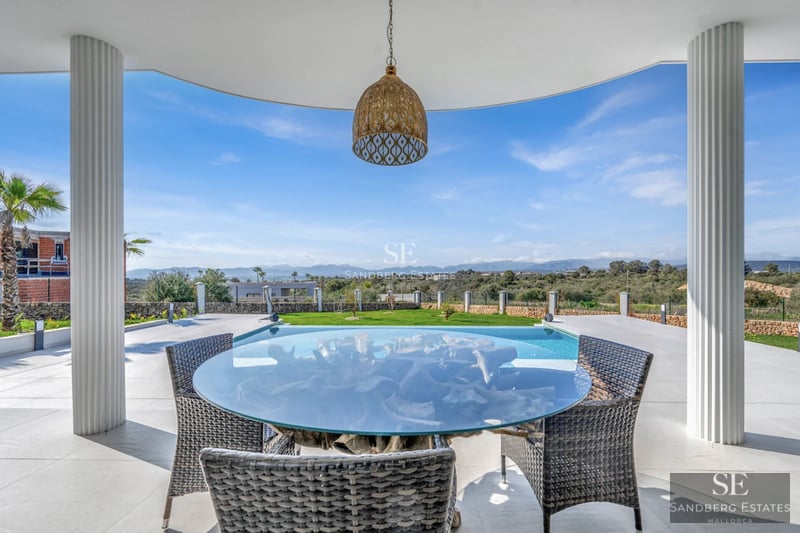Spacious living room with large windows, pool reflecting the light. Modern design with minimalist furniture and wood accents.