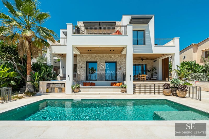 Vue extérieure d'une villa moderne avec piscine à débordement, jardin paysager et grandes baies vitrées. Design architectural minimaliste.