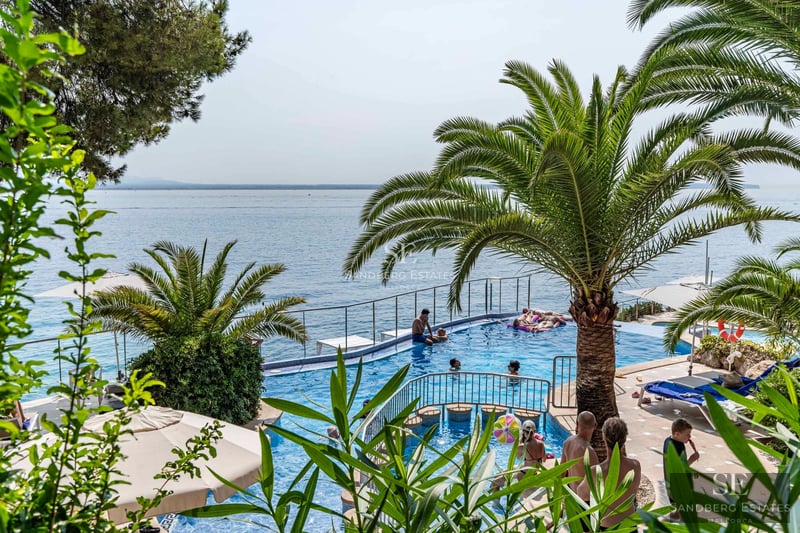 Exterior view of a modern villa with pool, landscaped garden, large windows, and minimalist design. Ambient lighting.