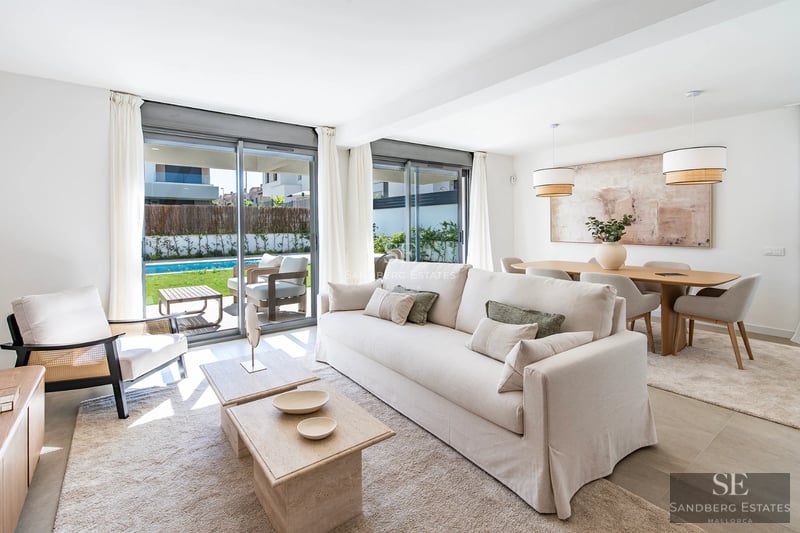 Large, reflective pool surrounded by minimalist terrace. Modern design, natural light, immaculate lawn and bright blue sky.