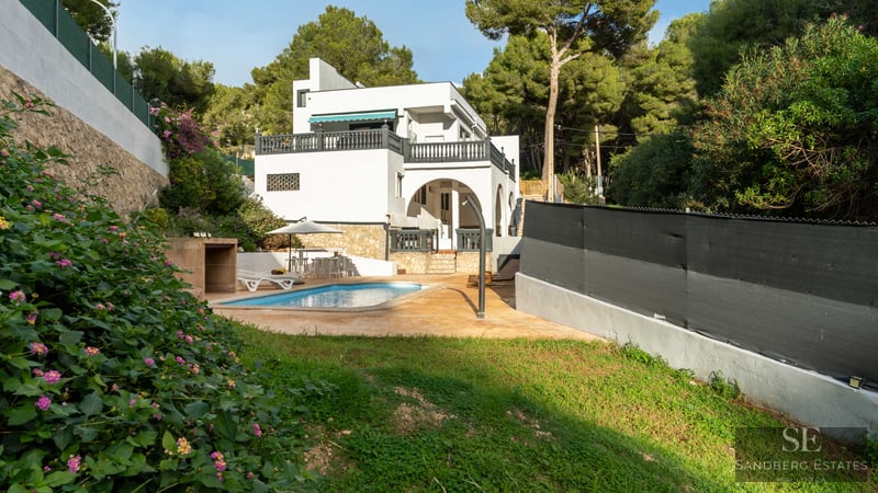 Villa blanche avec piscine privée, terrasse, pelouse et entourée d'une forêt de pins dense.