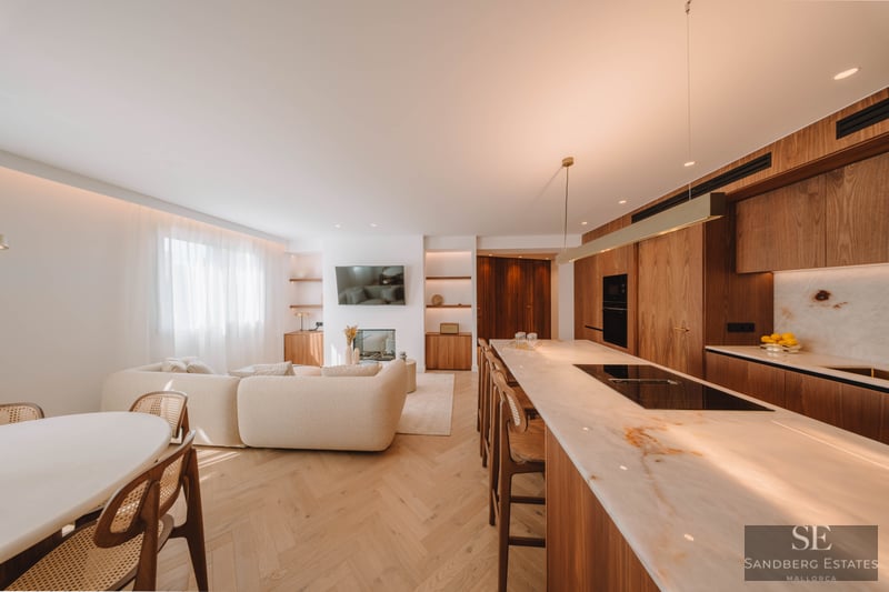Bright open-concept living area with a beige sofa, marble kitchen island, and warm wood flooring.