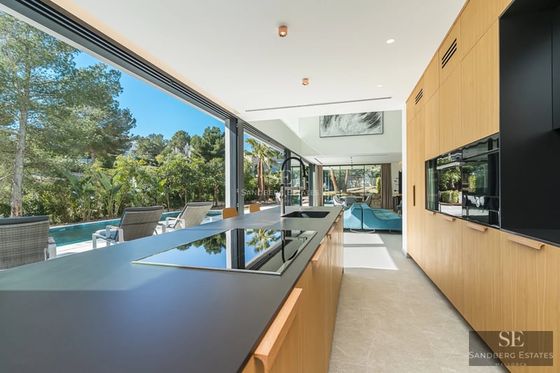 Exteriör av modern villa med infinitypool, stor trädgård och elegant arkitektur. Varm omgivningsbelysning och panoramautsikt.