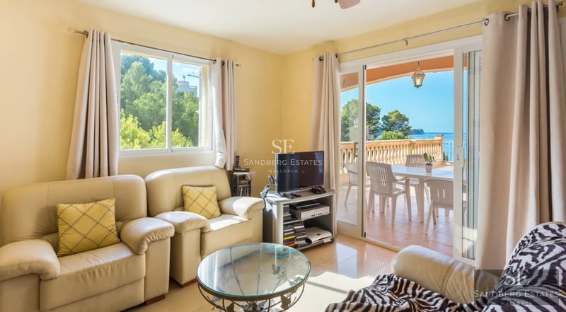 Bright interior with large windows, light wood flooring, and modern furniture. Panoramic sea views.