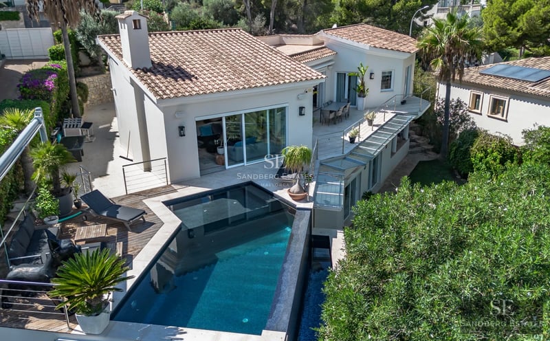 Spacious terrace with infinity pool and sea view. Modern furniture, glass railing and minimalist design.