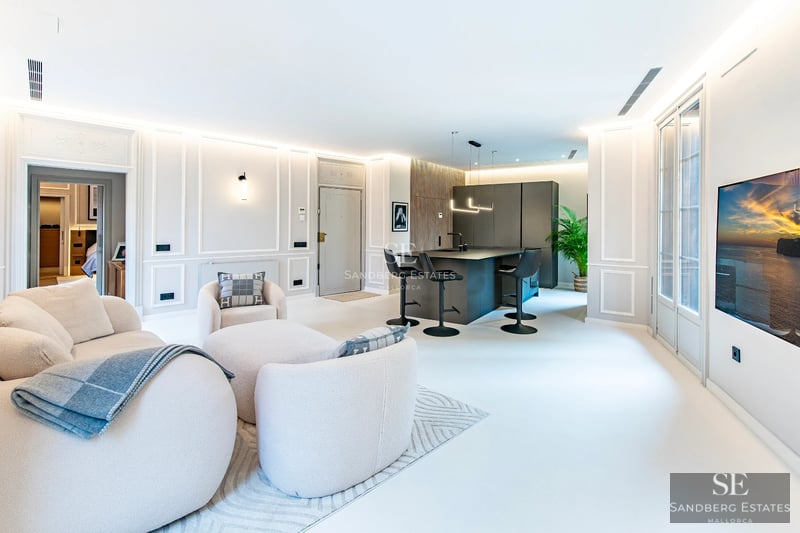 View of the infinity pool with glass edge, surrounded by cream-colored tiles. Modern, minimalist architecture with ocean views.