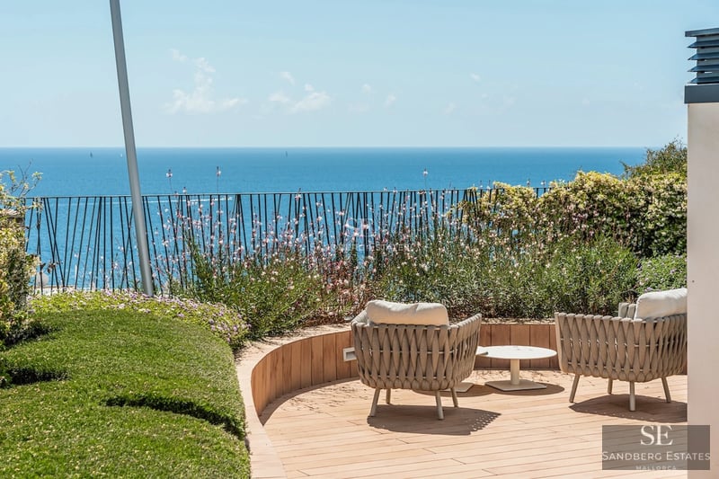 Spacious balcony with panoramic sea views. Modern design, glass railing, and tiled floor. Soft lighting and stylish furniture.