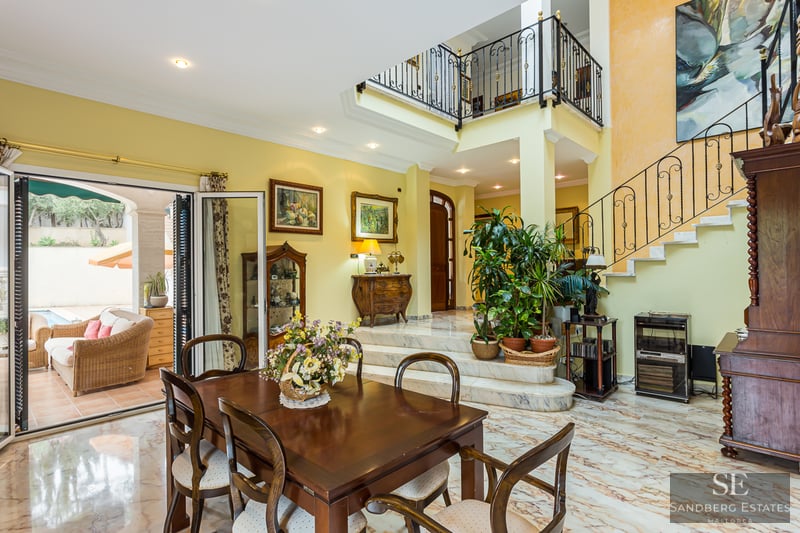 Grand dining room with marble floors, a wrought-iron staircase, and access to a terrace.