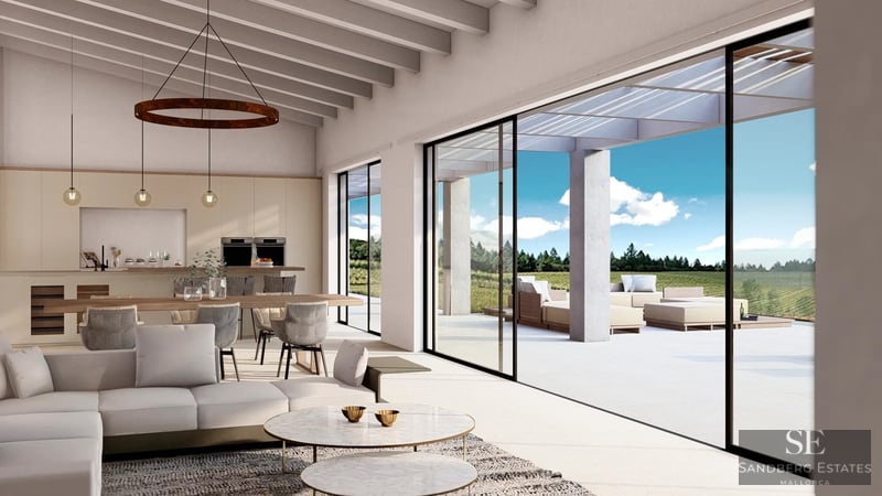 Bright living room with wooden beams, modern sofas, and large glass sliding doors opening to a sunny terrace.