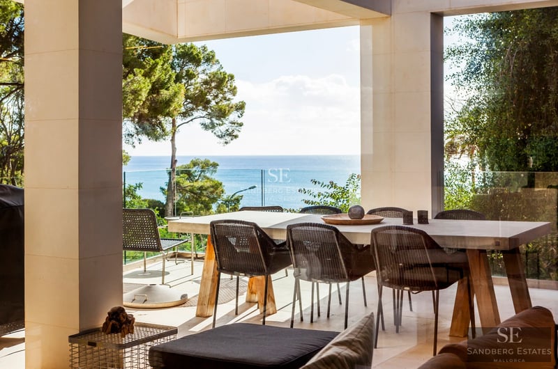 Spacious, bright living room with large windows overlooking a shimmering pool. Modern design with wood floors and elegant furnishings.