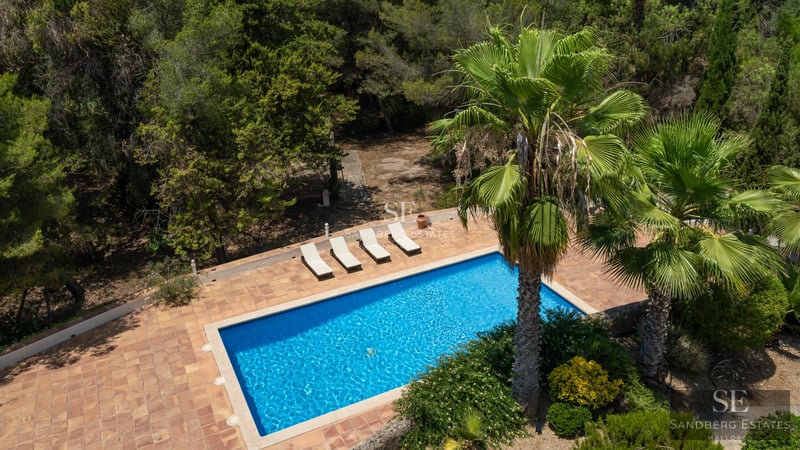 Vista exterior de villa moderna con piscina infinita, jardines exuberantes y amplias terrazas. Arquitectura contemporánea y acabados de lujo.