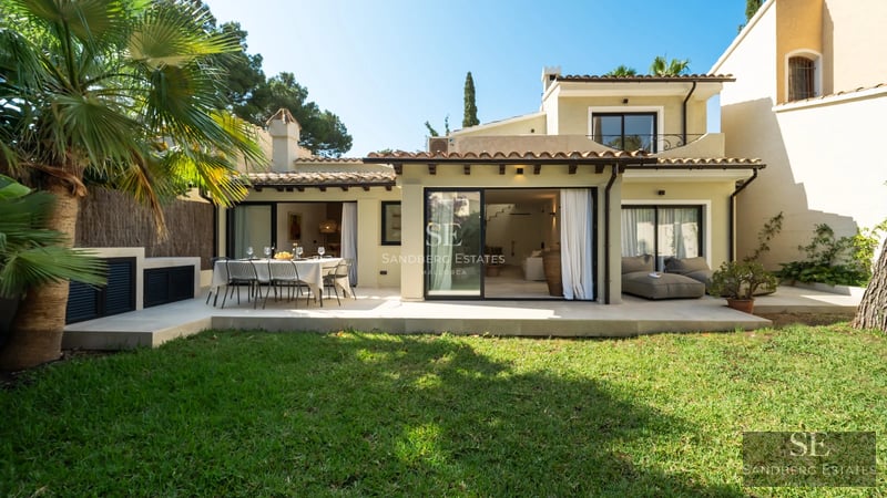 Exterior of a modern villa featuring a reflecting pool, expansive glass windows, and minimalist landscaping. Soft ambient lighting.