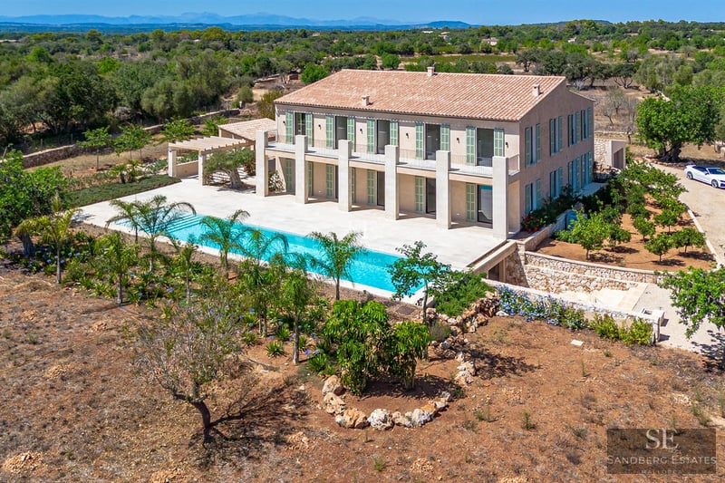 Spacious living room with large windows overlooking an infinity pool. Modern and elegant design with abundant natural light.